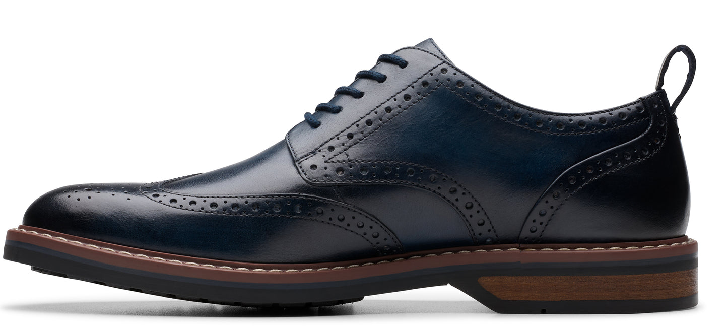 A dark blue leather dress shoe with decorative perforations along the edges.