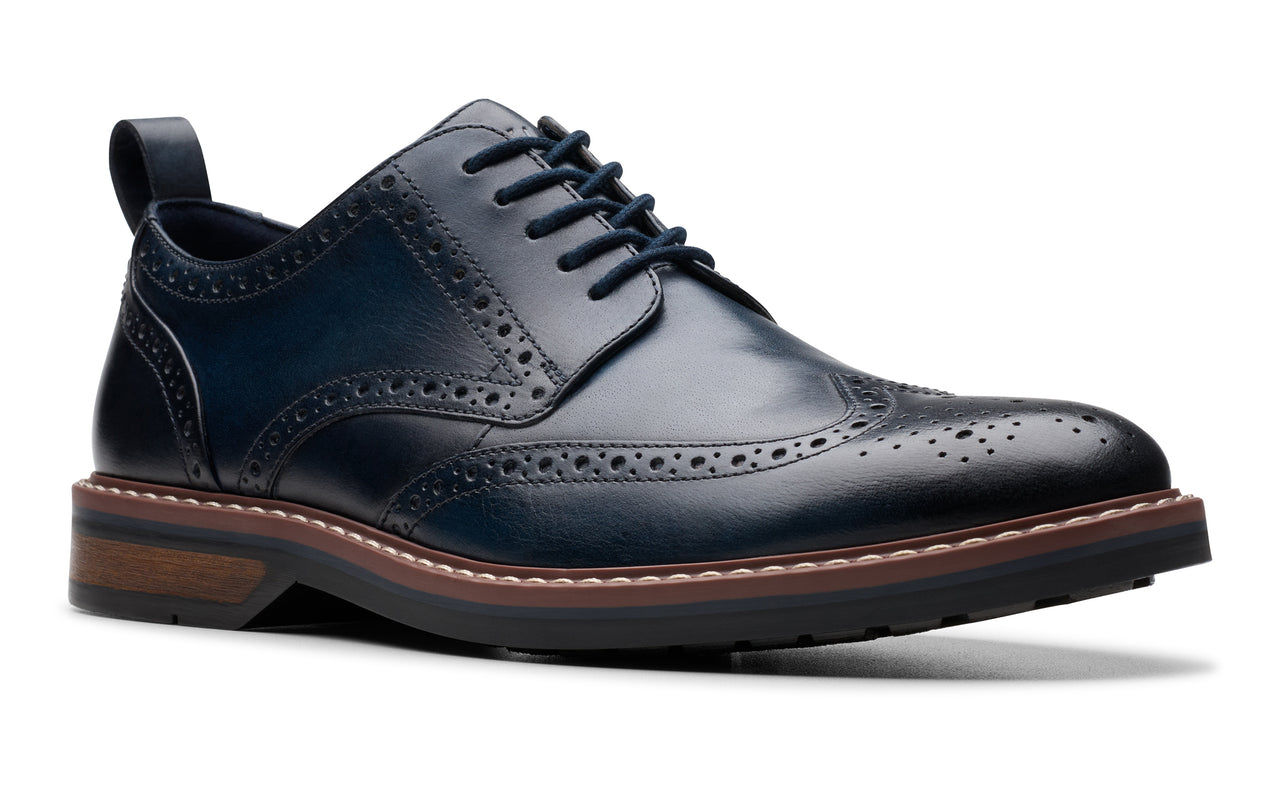 Navy blue leather wingtip dress shoe with a black lug sole.