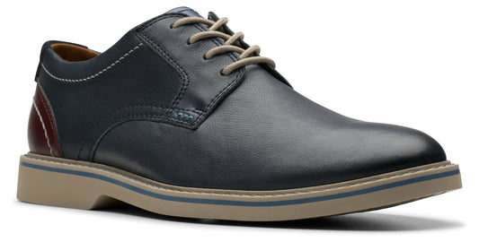 A navy blue leather oxford shoe with beige laces and a tan sole with a blue accent stripe.