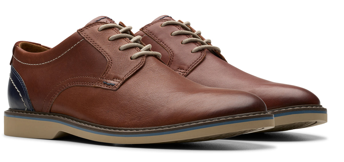 A pair of brown leather dress shoes with light beige laces and a stacked sole.
