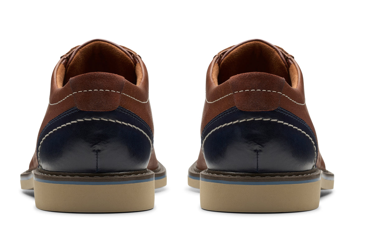 Back view of two brown and navy shoes with stitching and light-colored soles.