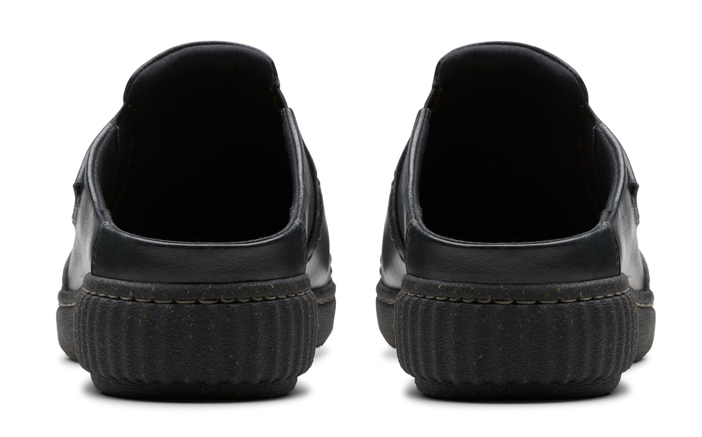 Pair of black slip-on shoes, rear view showing the thick, ridged soles and rounded heel.