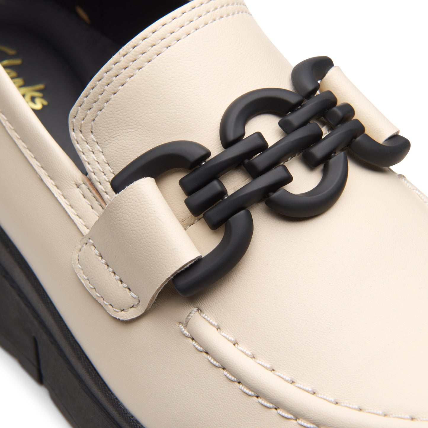 Close-up of an off-white loafer with a black chain-link embellishment.