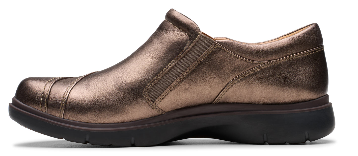 A slip-on shoe in bronze color with a rounded toe and a dark-colored sole.