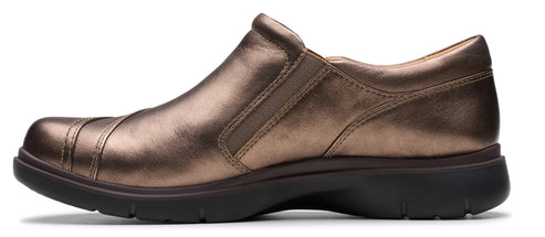 A slip-on shoe in bronze color with a rounded toe and a dark-colored sole.