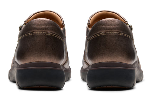 Pair of metallic bronze leather shoes with black soles, viewed from the back.