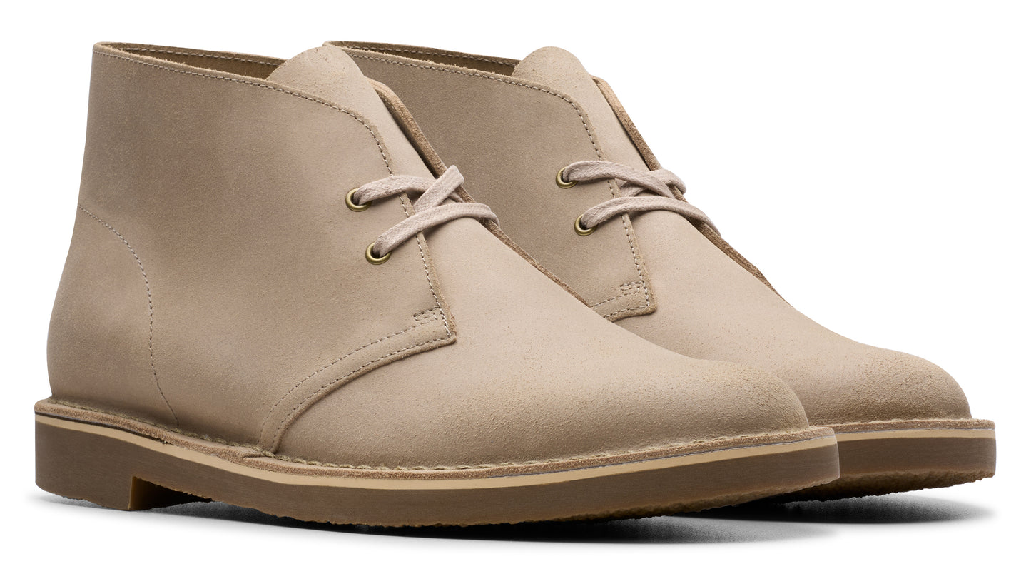 Two beige leather chukka boots with brown soles.
