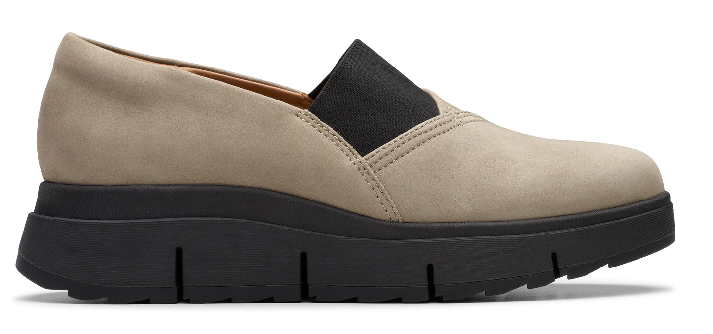 A low-top tan slip-on shoe with black elastic and a thick, ridged black sole.