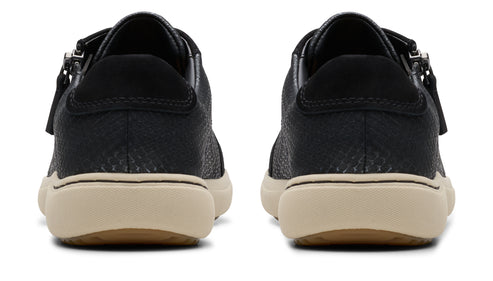 Two black shoes with beige soles, seen from the back. Each has a zipper on the side.