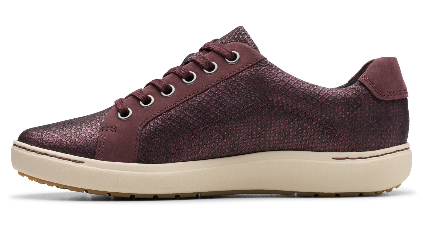 A woman's oxblood casual sneaker with a textured upper and a flat, off-white sole.