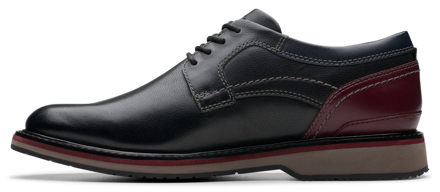 A black leather dress shoe with a burgundy accent.