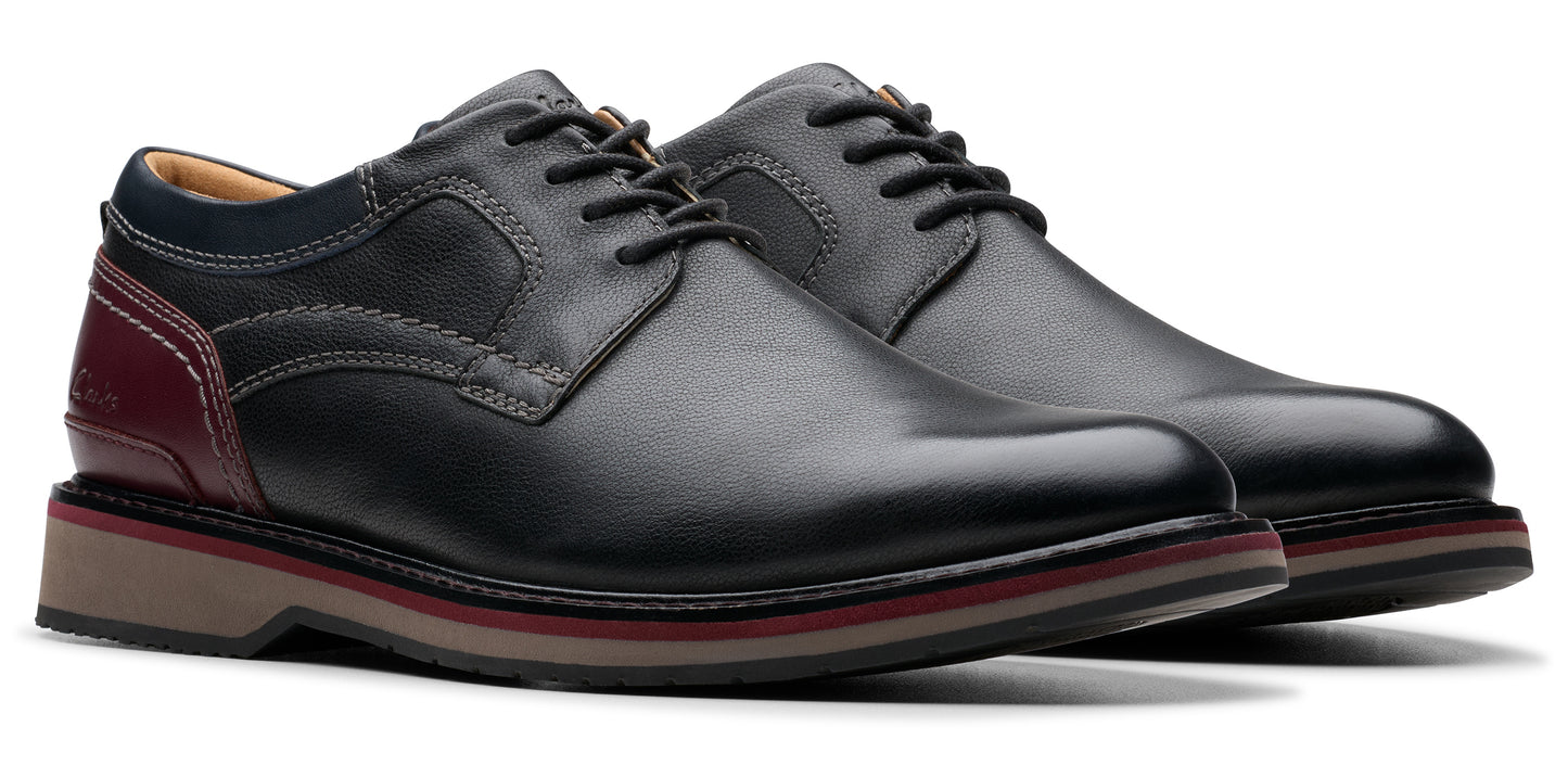 A pair of black leather dress shoes with black laces and a light-colored sole.