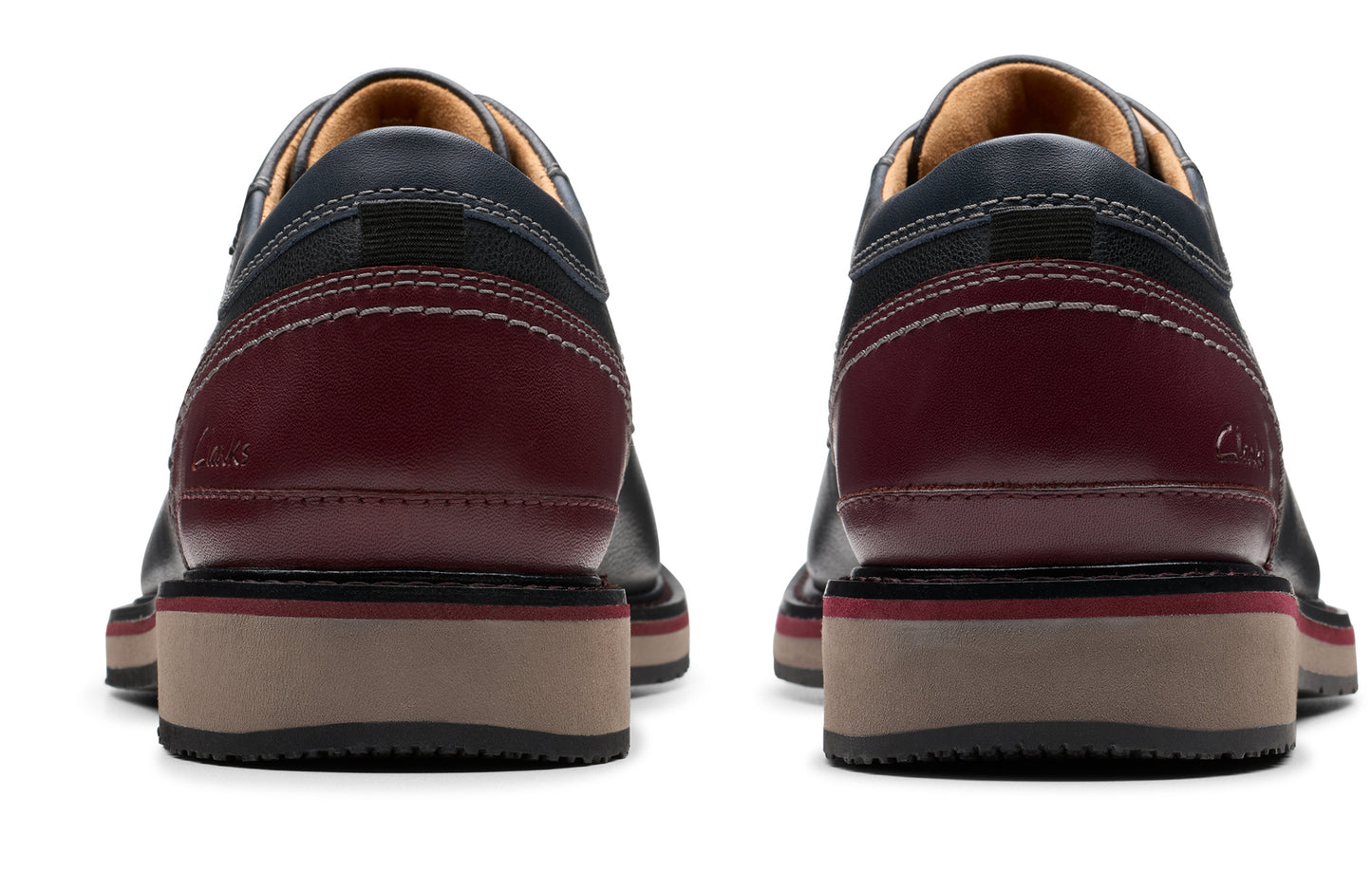Rear view of two dress shoes, navy blue leather upper with dark burgundy heel and beige sole.
