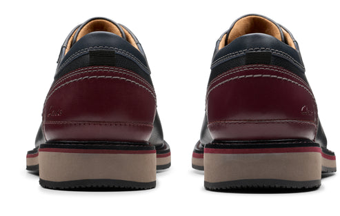 Rear view of two dress shoes, navy blue leather upper with dark burgundy heel and beige sole.