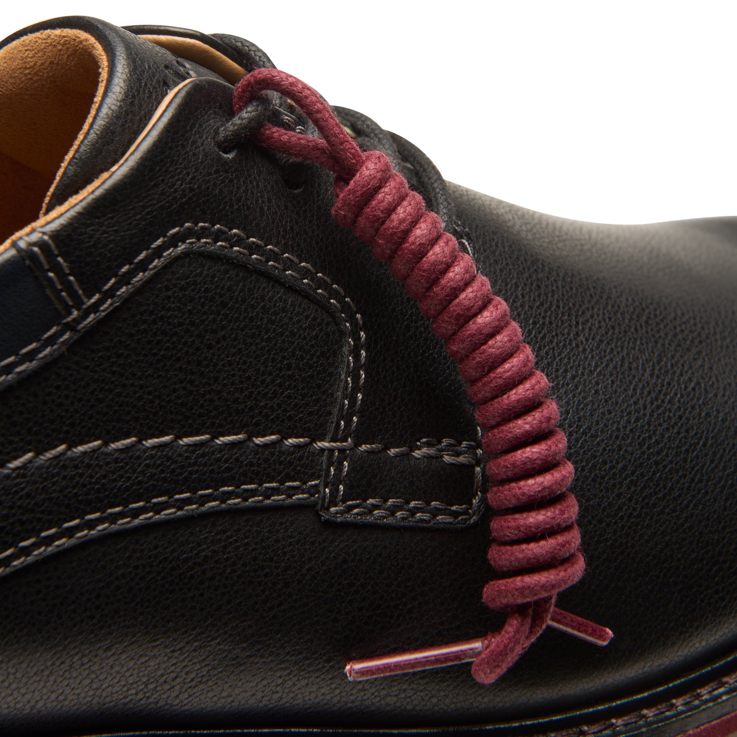 Close-up of a black leather shoe with a burgundy spiral shoelace.