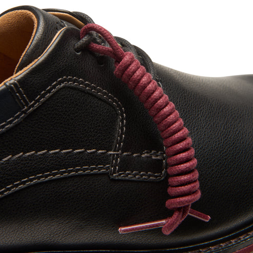 Close-up of a black leather shoe with a burgundy spiral shoelace.