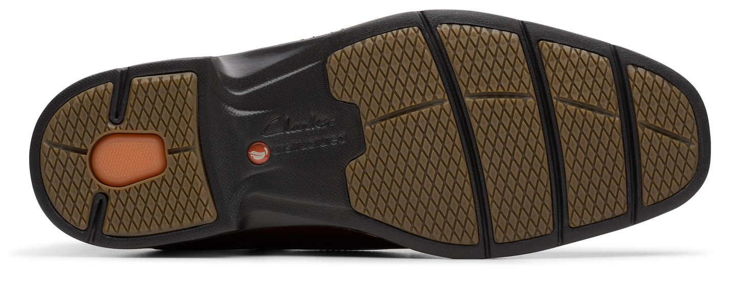 A brown textured sole of a shoe with the brand printed in the middle.
