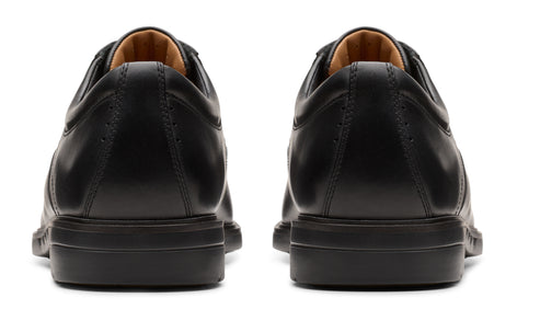 A pair of black leather shoes, viewed from the back, showcasing their smooth texture and simple design.