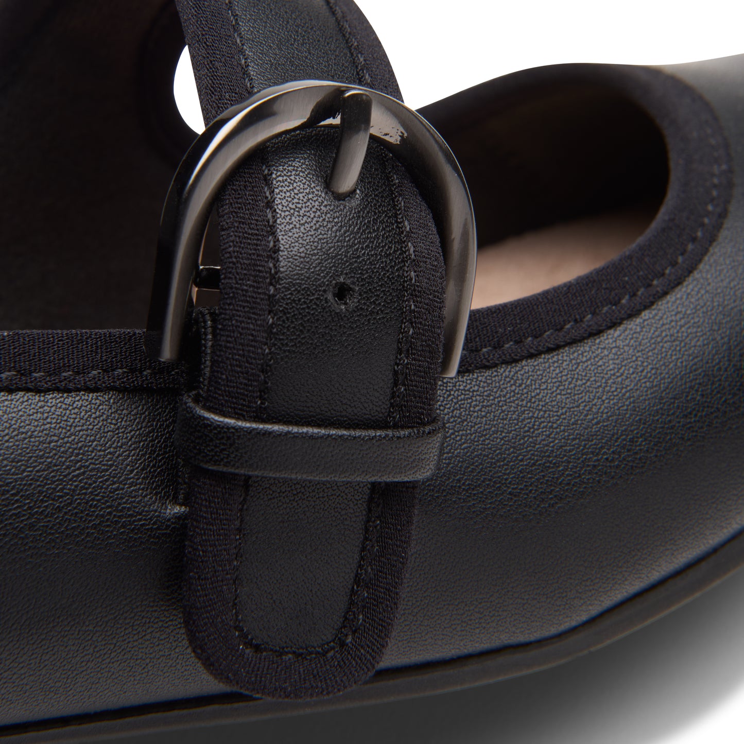 Close-up of a black Mary Jane shoe buckle with black fabric trim.