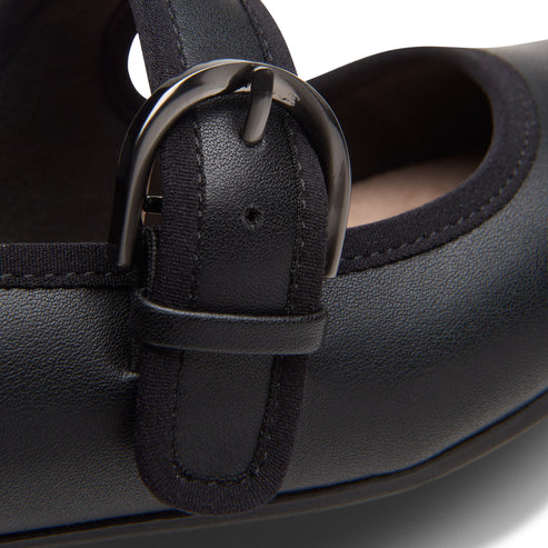 Close-up of a black Mary Jane shoe buckle with black fabric trim.