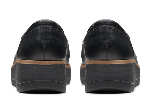 Two black leather loafers with a platform sole, rear view.