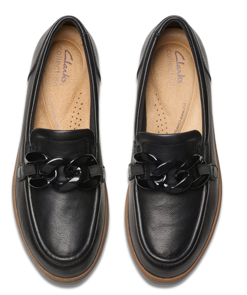 Overhead view of black leather loafers with a black chain across the top of the vamp.