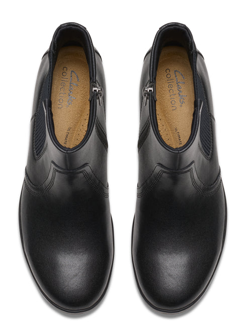 Top-down view of a pair of black, low-heeled, ankle boots with side zippers and elastic side panels; the insole reads "clarks collection".