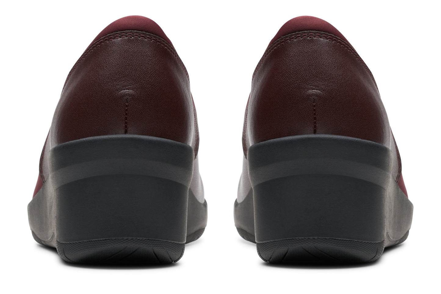 Pair of dark red leather pumps with low wedge heel, back view.