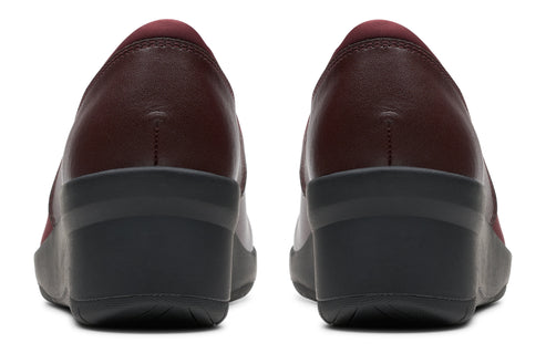 Pair of dark red leather pumps with low wedge heel, back view.