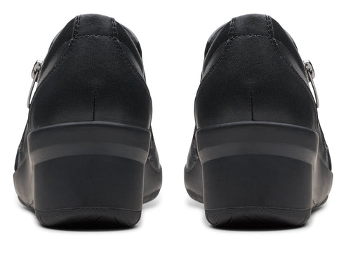 Pair of black leather wedge shoes, seen from the back, with side zipper.