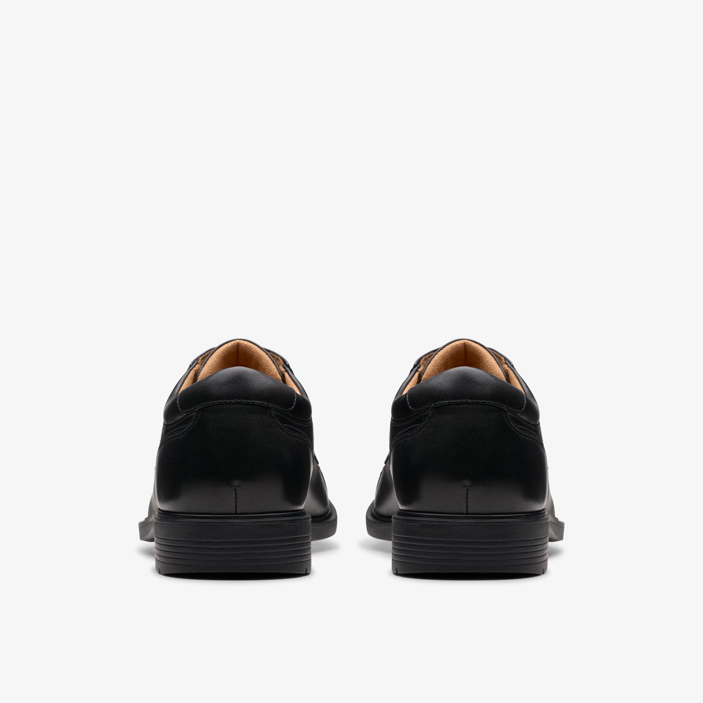 Rear view of two identical black leather dress shoes.