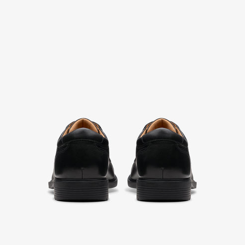 Rear view of two identical black leather dress shoes.