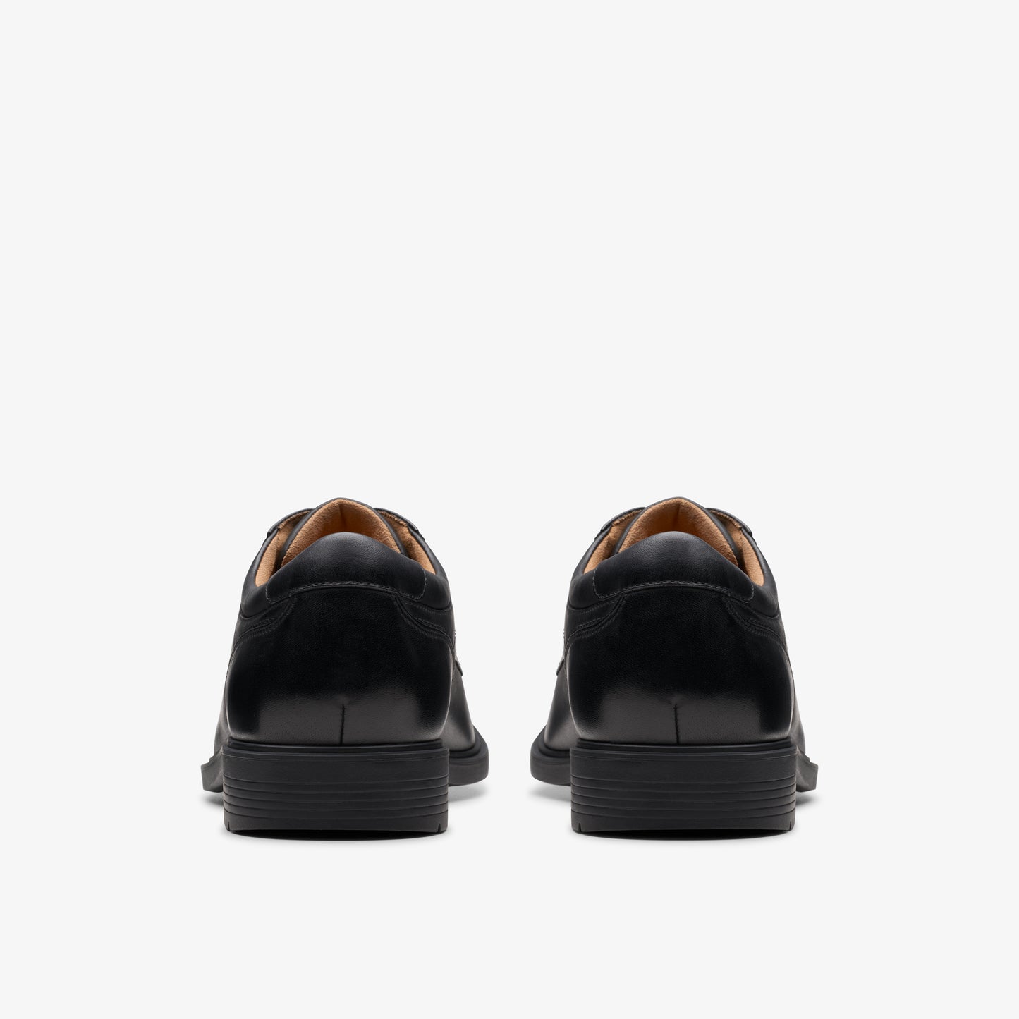 Rear view of two identical, black formal shoes with lace up closure.