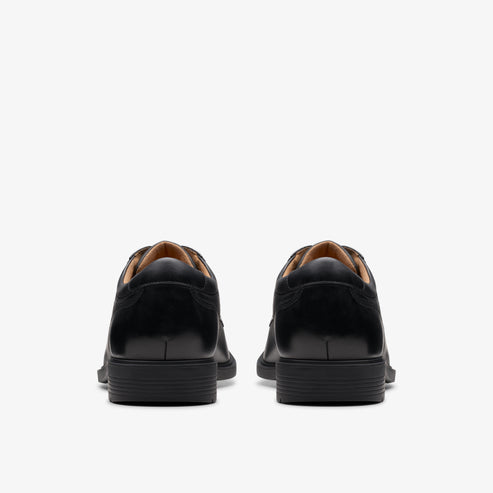 Rear view of two identical, black formal shoes with lace up closure.