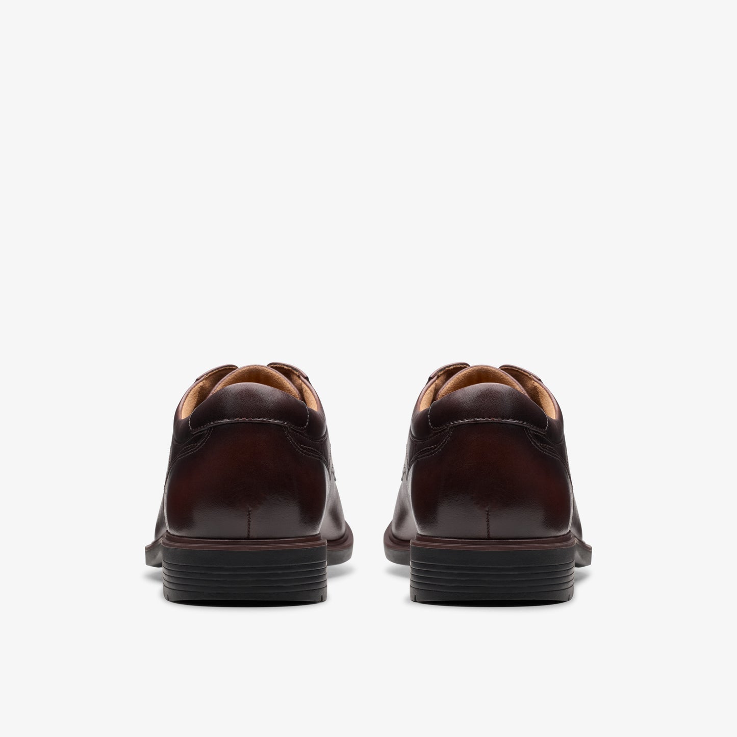 Rear view of a pair of brown leather dress shoes with black soles.