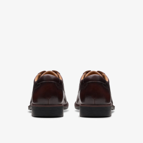 Rear view of a pair of brown leather dress shoes with black soles.