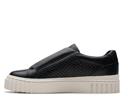 A black slip-on sneaker with a woven pattern on the side, and a thick white sole.