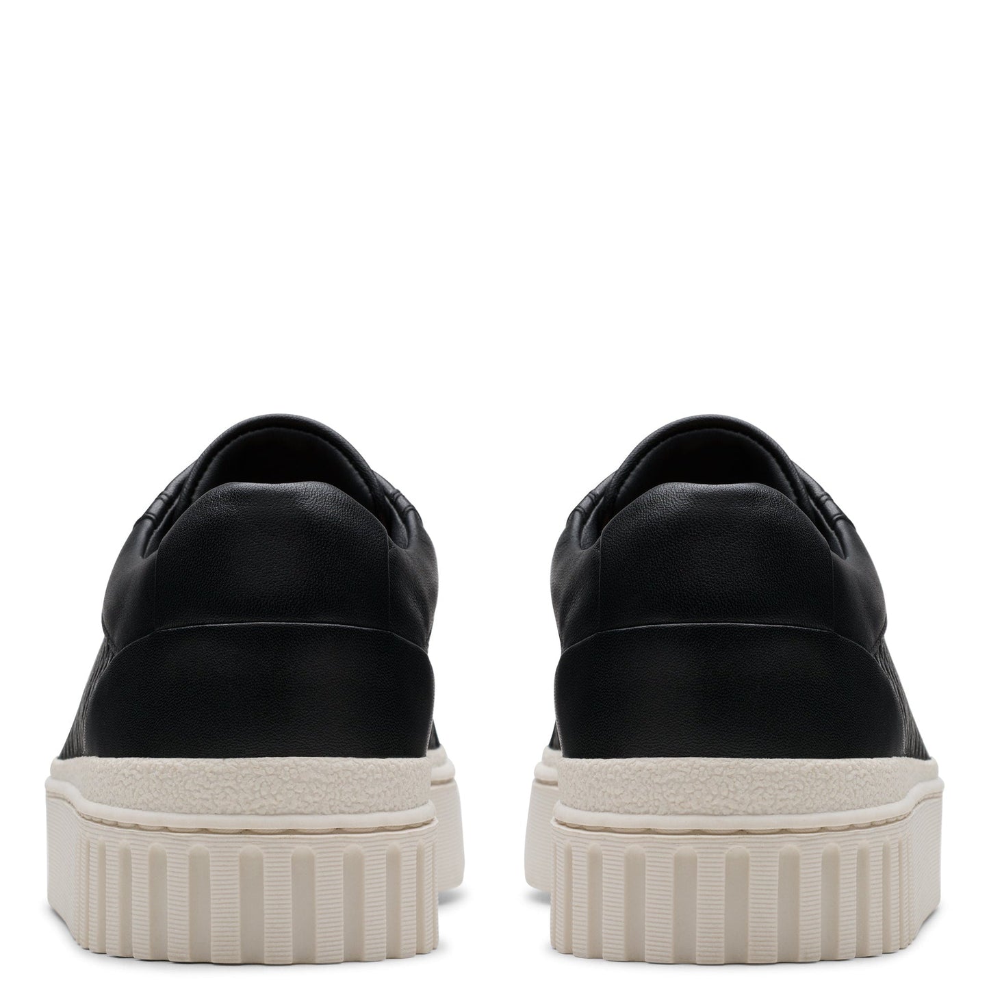A pair of black, low-cut sneakers with thick, ridged, off-white soles, viewed from the back.