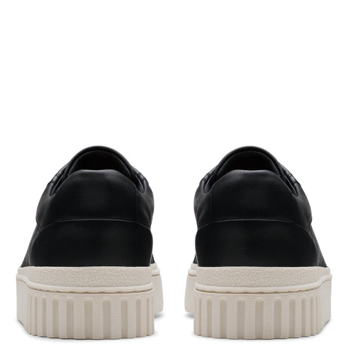 A pair of black, low-cut sneakers with thick, ridged, off-white soles, viewed from the back.