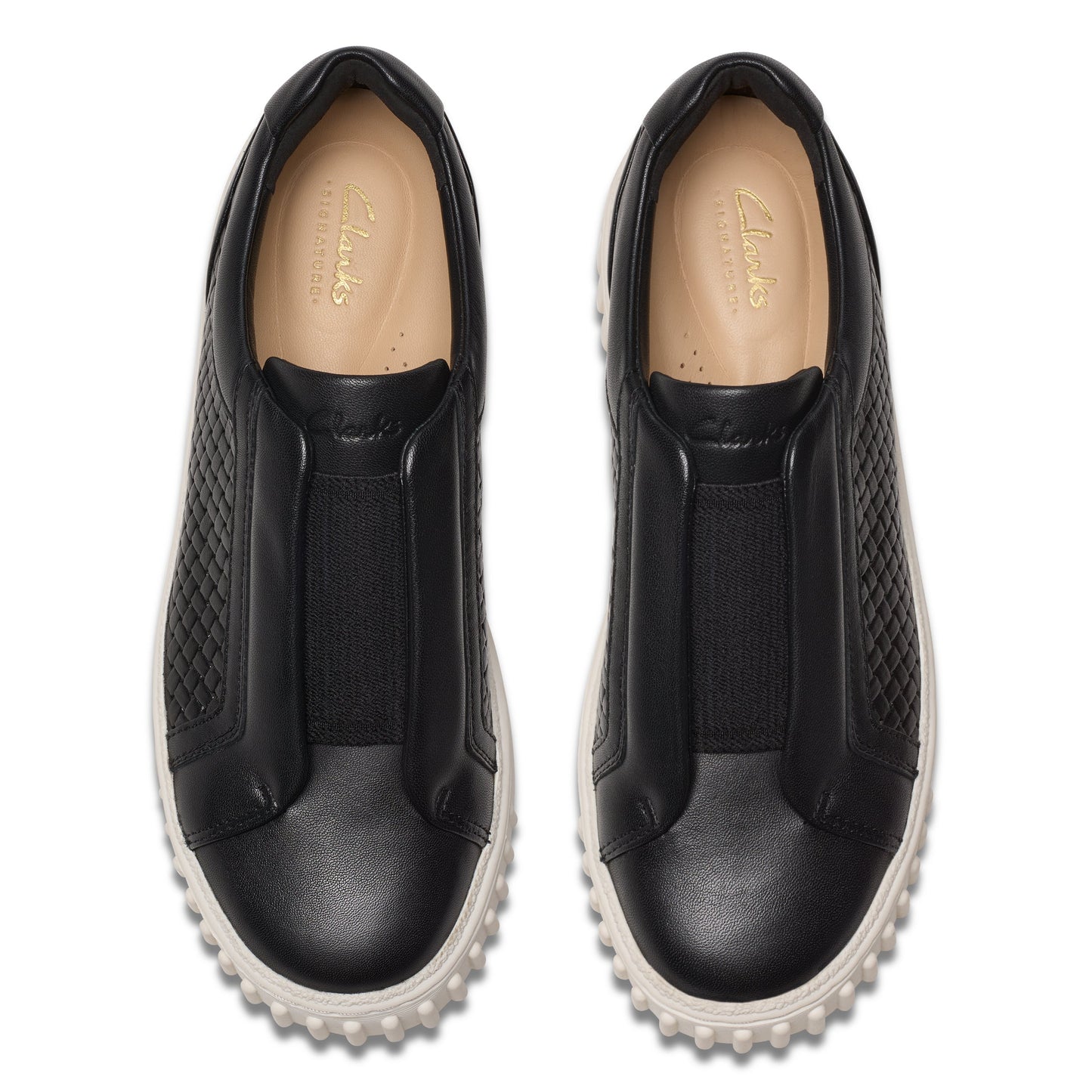Pair of black leather slip-on shoes with textured quilted side panels and white soles.