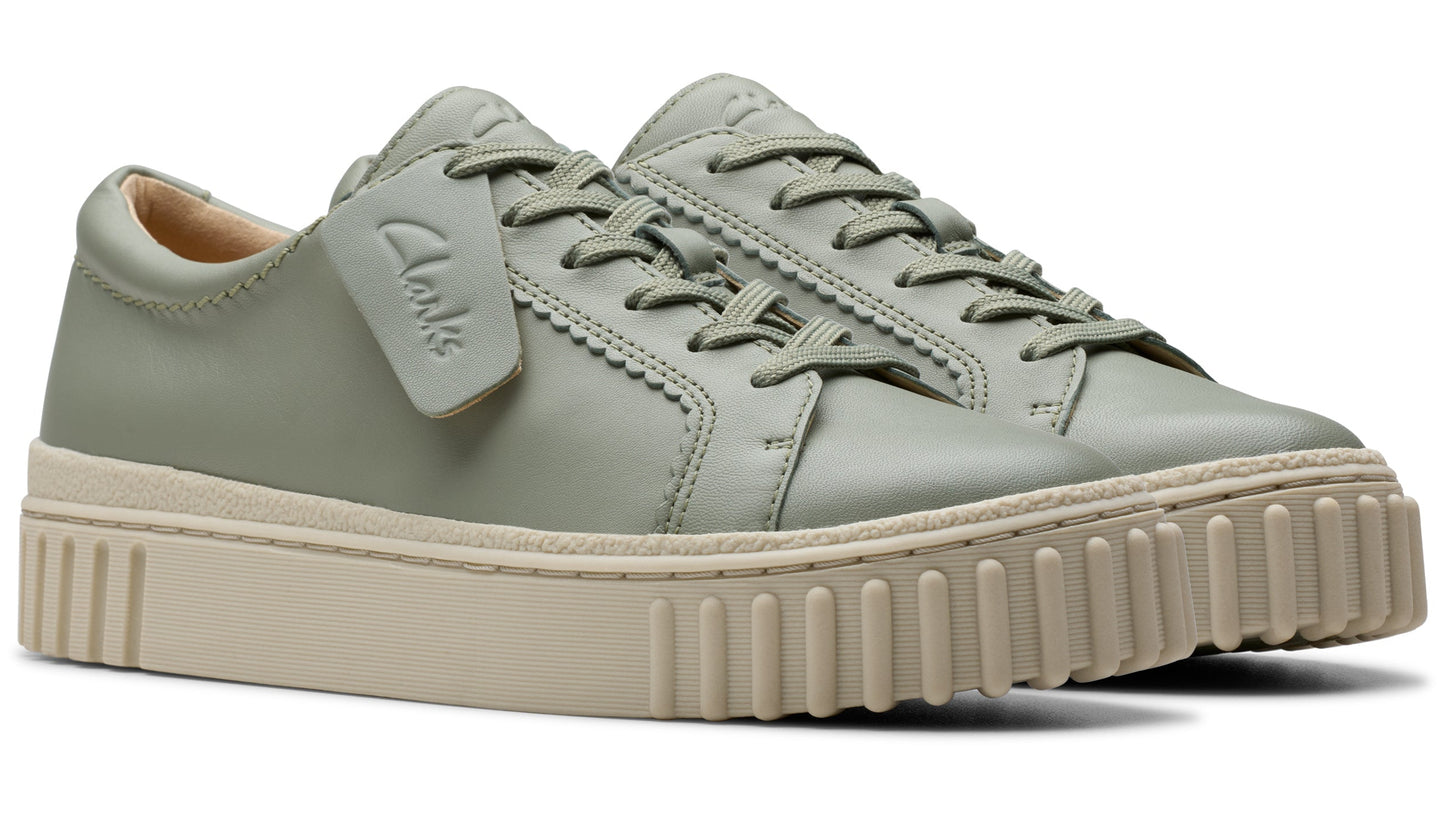 A pair of light green leather sneakers with a thick, beige, ribbed sole and laces.