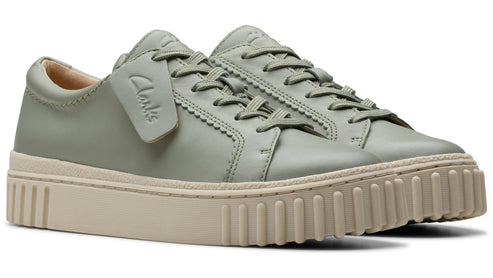 A pair of light green leather sneakers with a thick, beige, ribbed sole and laces.