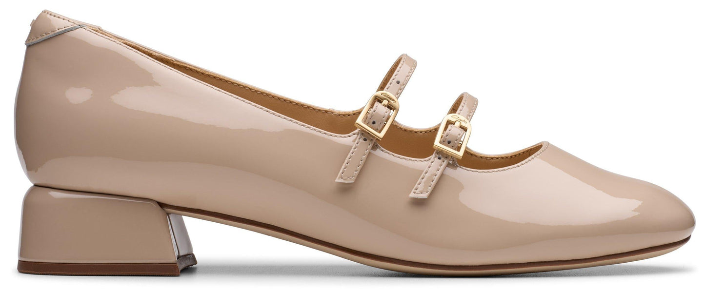 Beige patent leather Mary Jane shoe with a square heel and two straps with gold buckles.