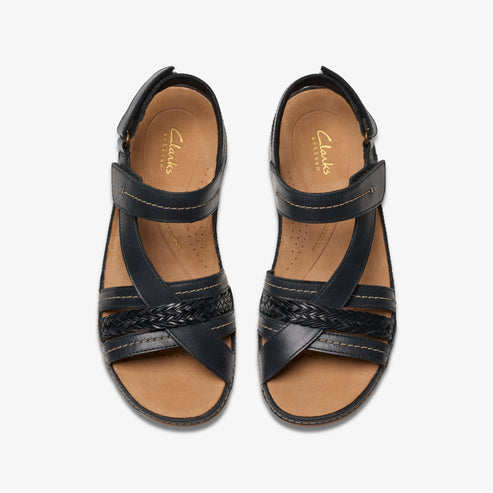 Top-down view of black leather sandals with a braided detail across the toes and a Velcro strap at the ankle.