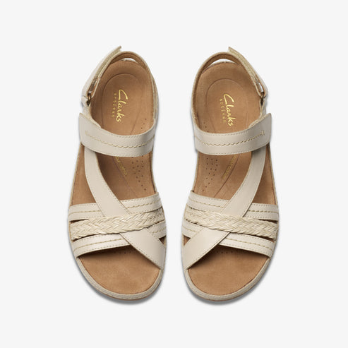 Top-down view of two cream-colored sandals with crisscrossing straps and velcro closures.