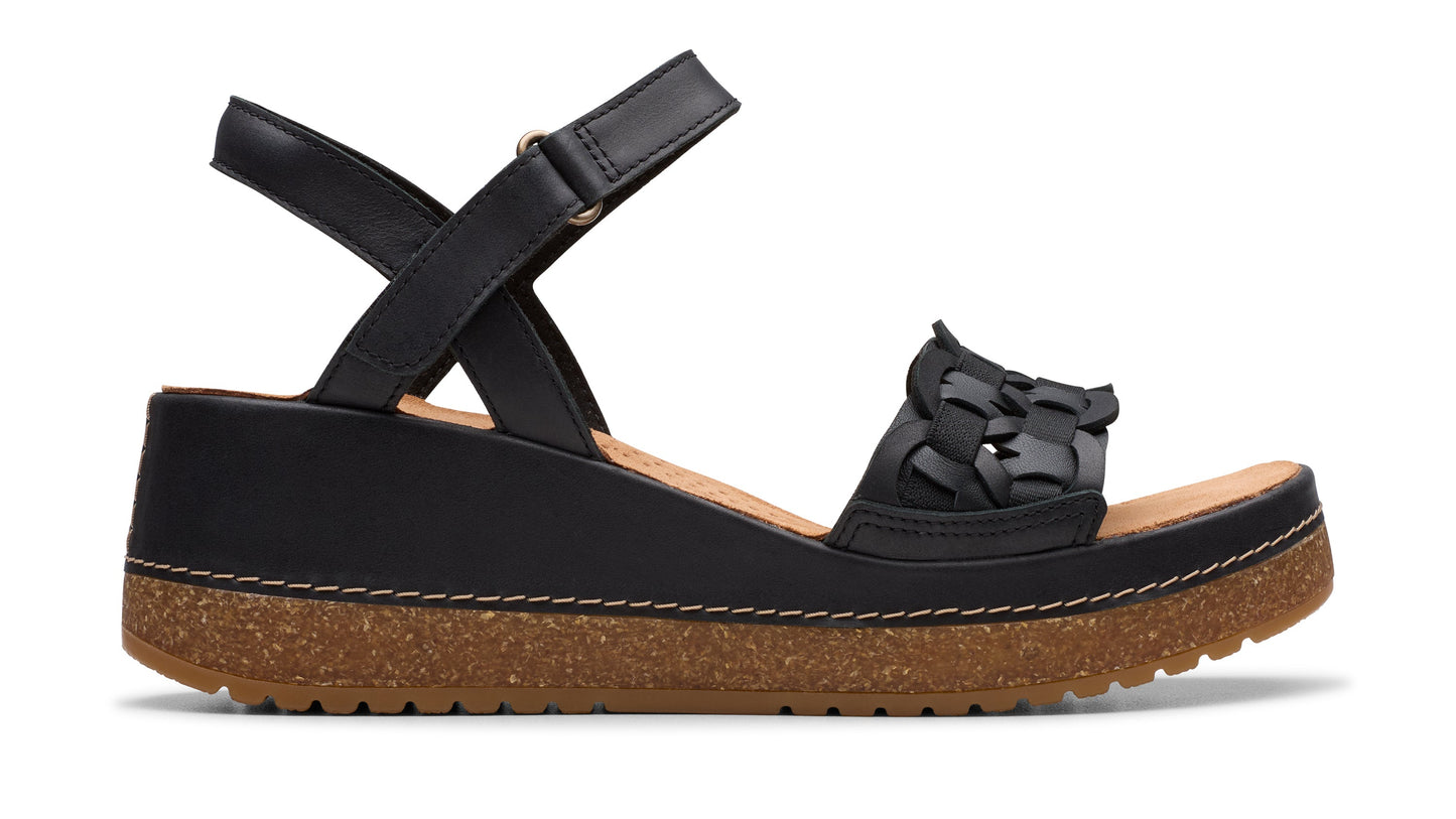 Black wedge sandal with decorative woven straps, an ankle strap, and a cork-trimmed sole.