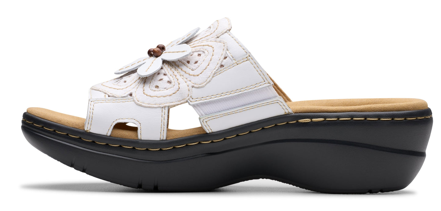 White sandal with flower detail on the vamp and black sole.