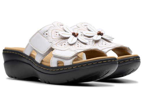 White slide sandals with floral embellishments and adjustable straps.