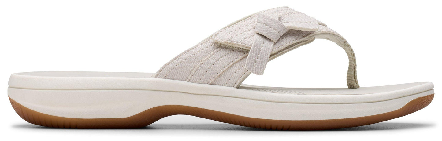 A sandal with a white upper and brown sole.
