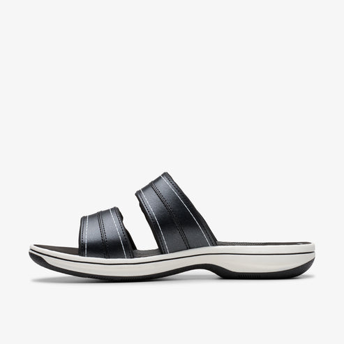 Black slide sandals with white stitching and a white sole.